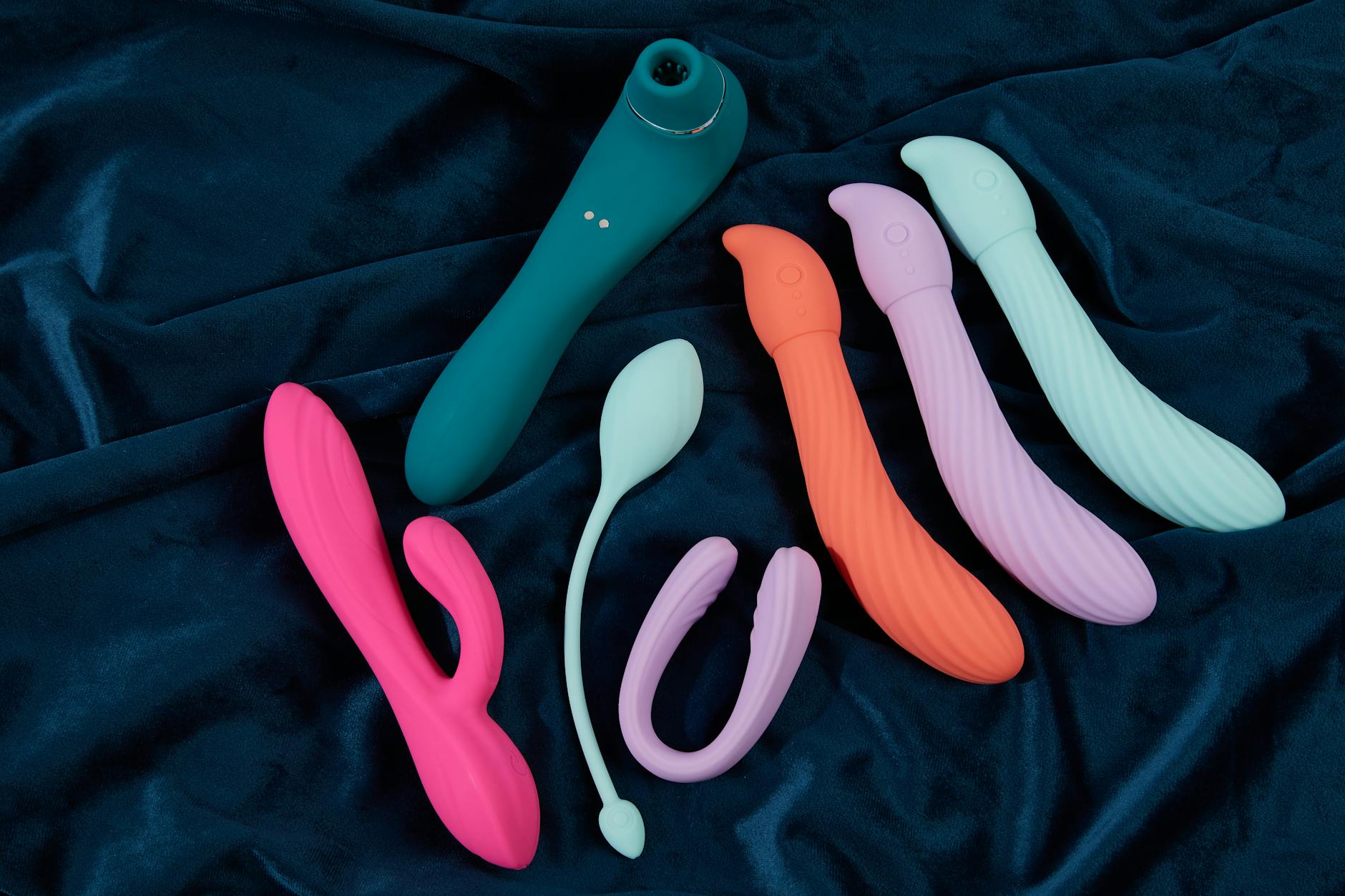 A silicone clitoral vibrator held in hand against a solid background, representing self-care and intimate wellness