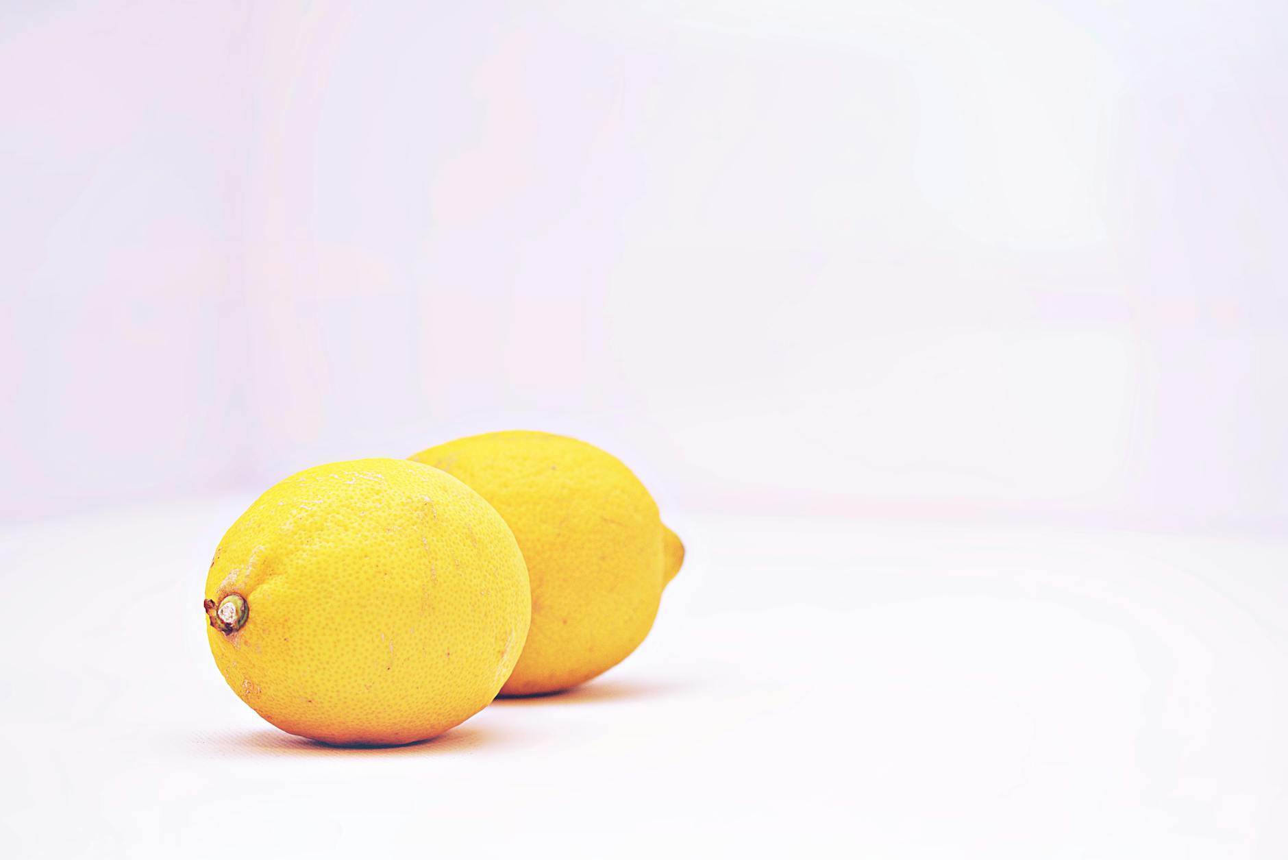 A yellow silicone vibrator surrounded by fresh fruit on a bright yellow background