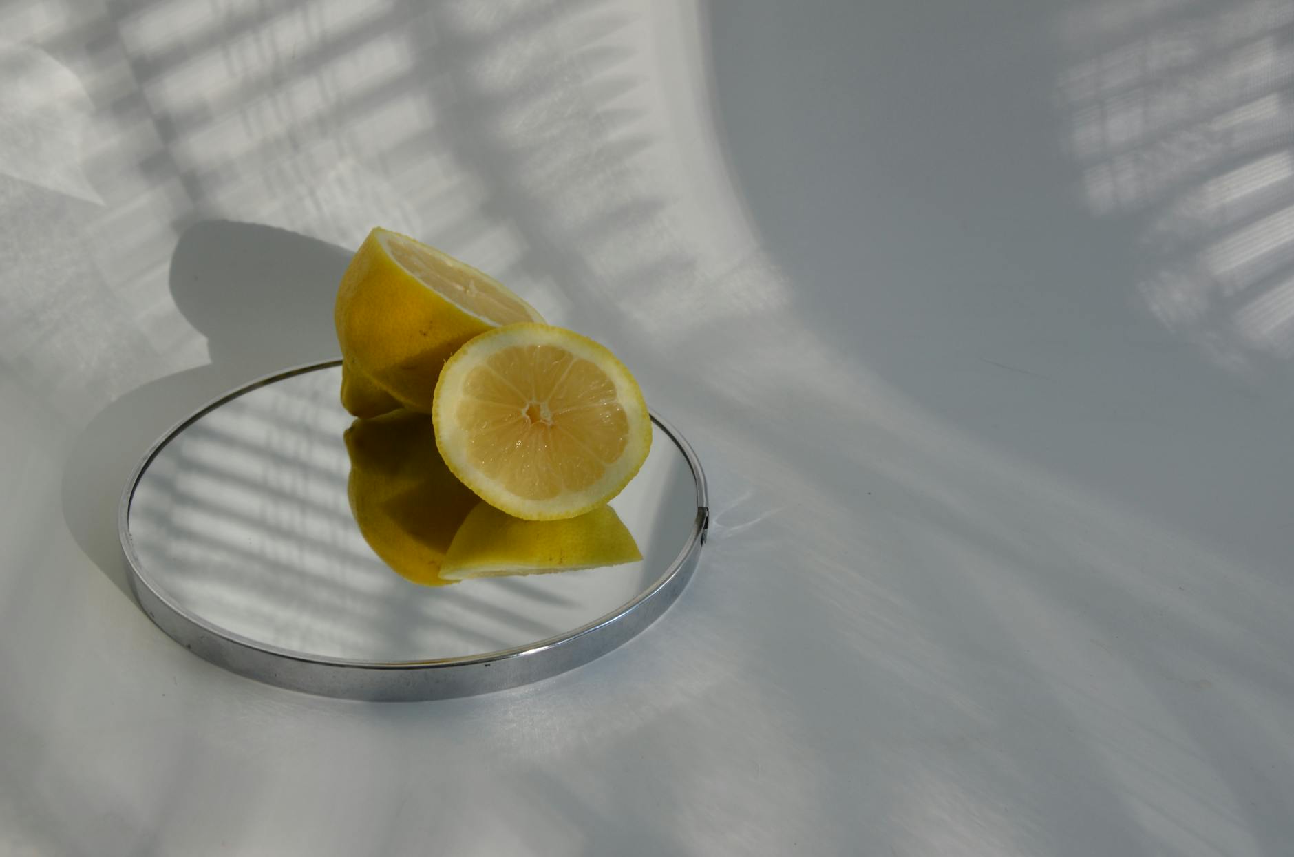 Sliced lemons on a mirror casting shadows, showcasing minimalistic sensuality