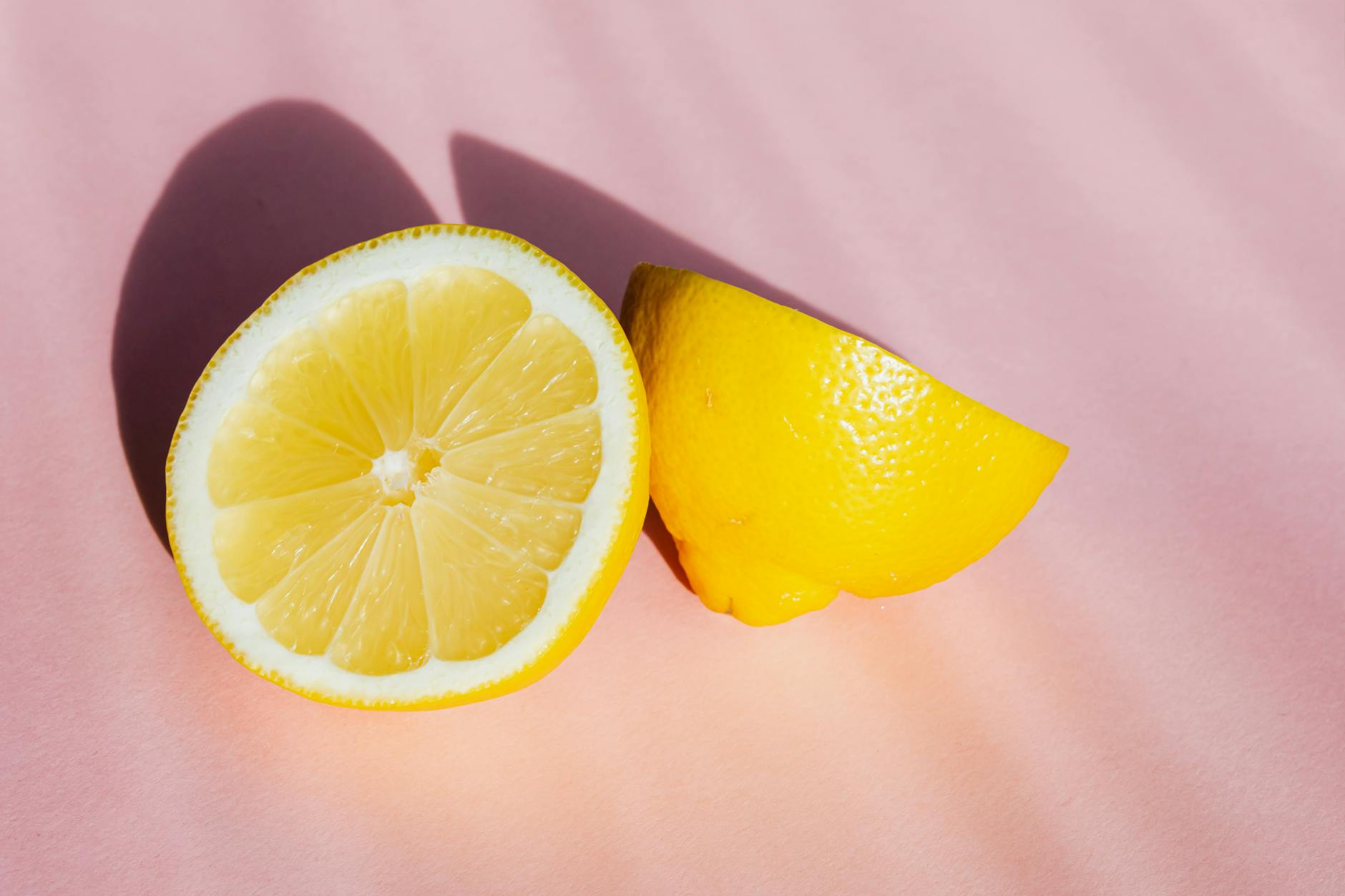 Fresh lemon halves on a pink background in natural light, representing sensitivity and renewal