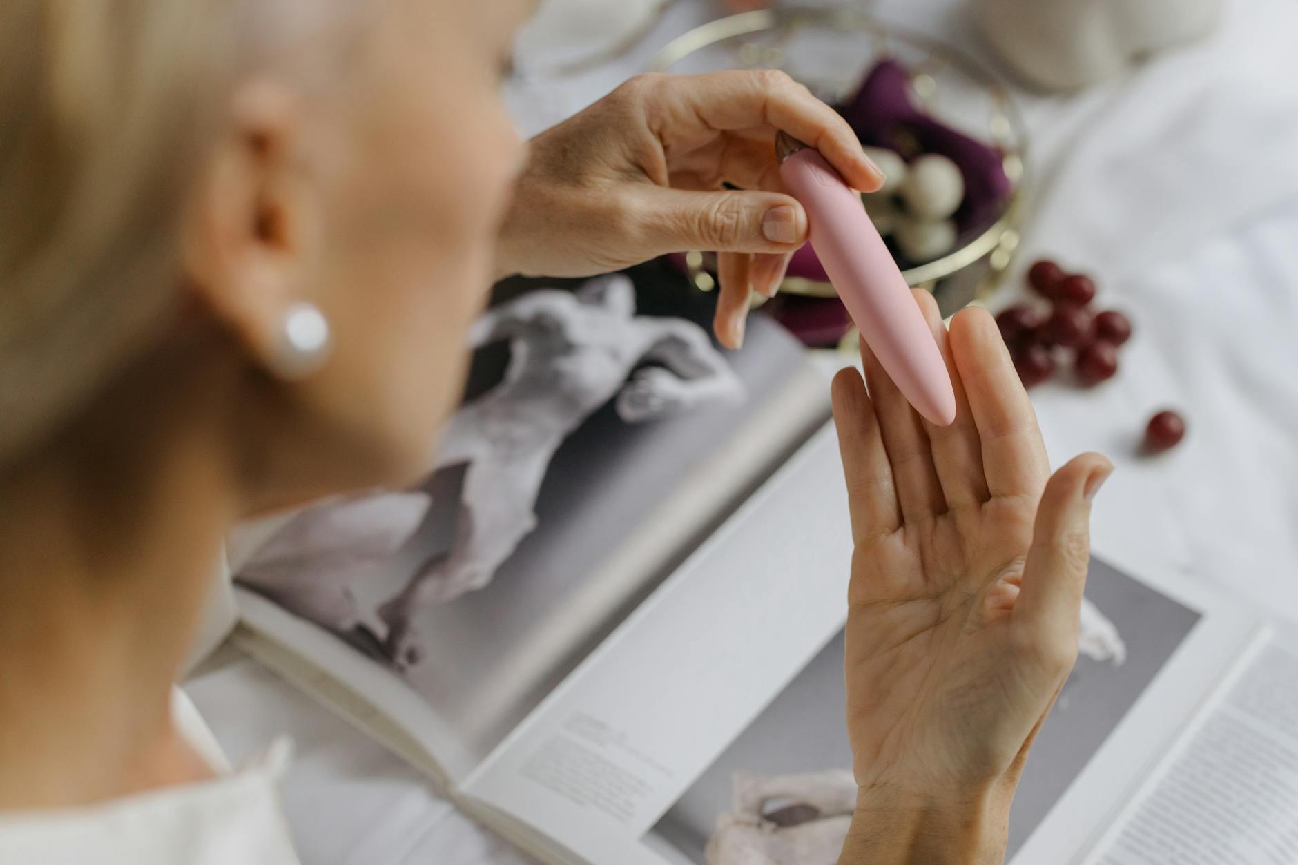Close-up of a woman holding a vibrator with personal items nearby, emphasizing reconnection and intimate self-discovery.