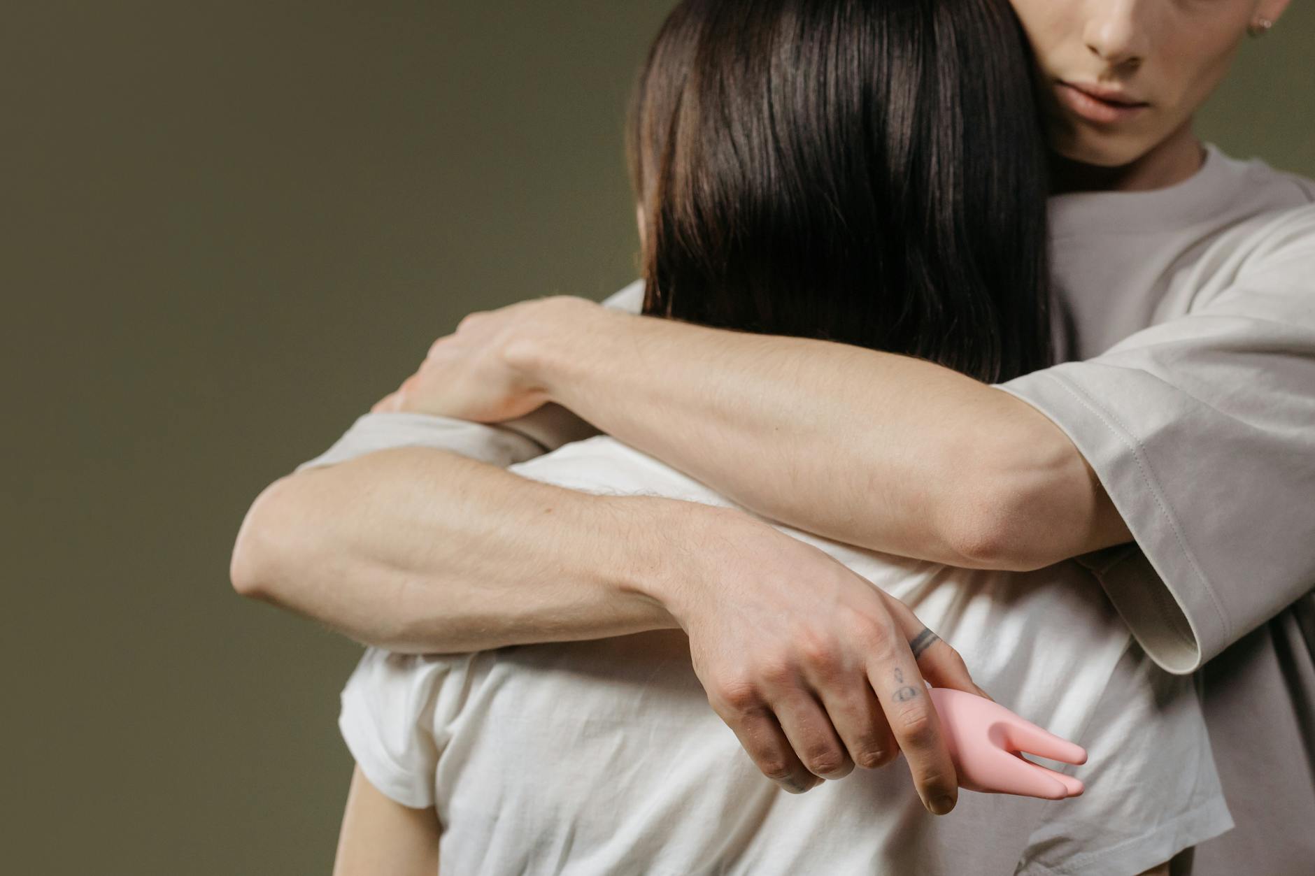 Casal abraçado intimamente com vibrador clitoral, demonstrando confiança e exploração conjunta